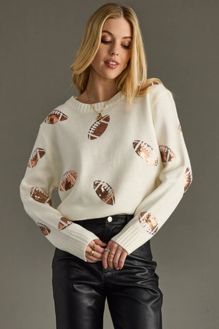 Woman wearing a cream sweater with football patterns on a gray background